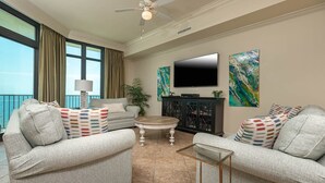 A living room with two grey sofas, a coffee table, a TV, and artwork on the walls. - Come RELAX on the LAZY RIVER! Phoenix West 3BR (Orange Beach)