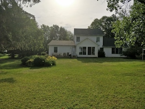 A two-story house with a large front lawn, a small porch, and a garage.