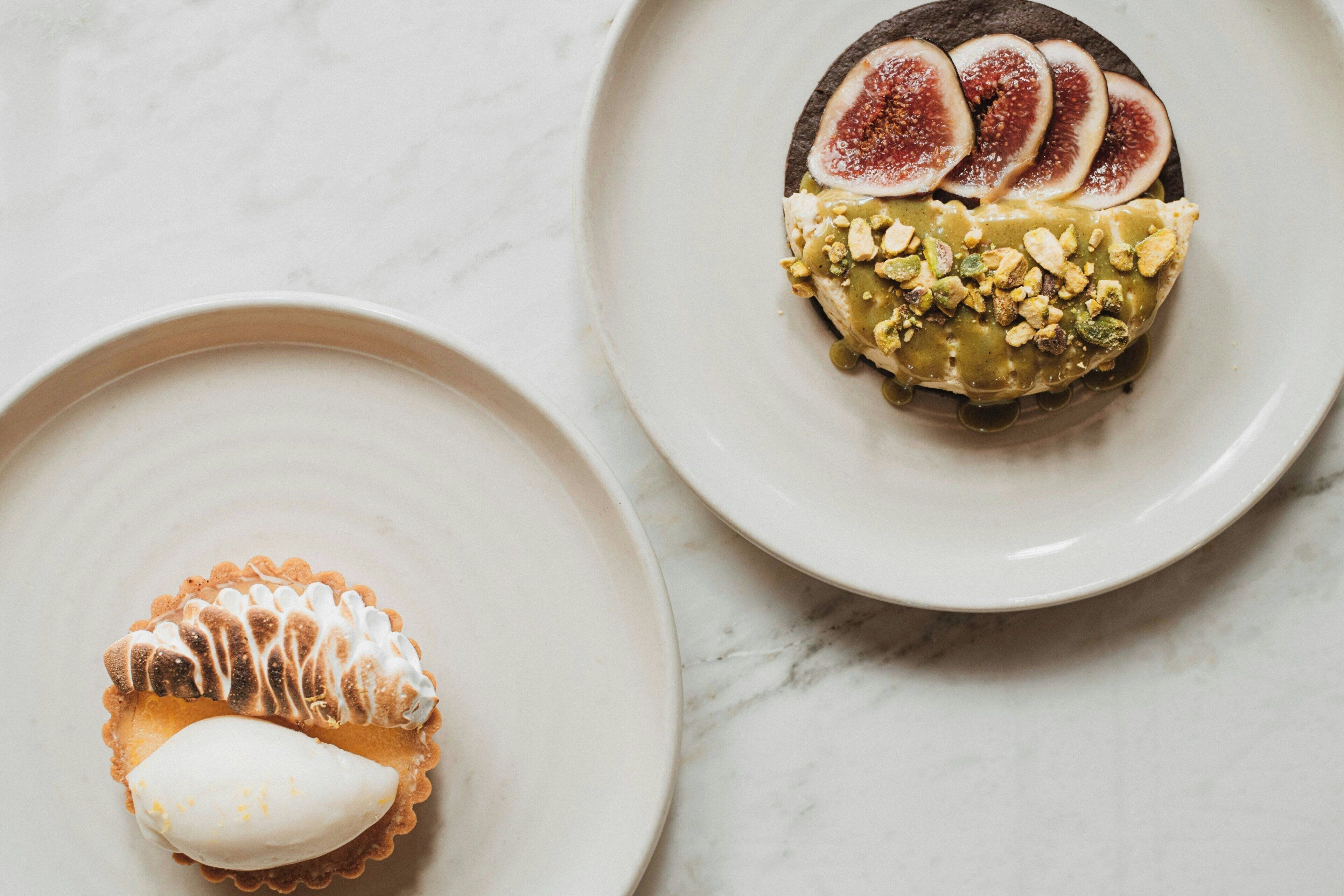 Two plates with desserts on a marble surface.