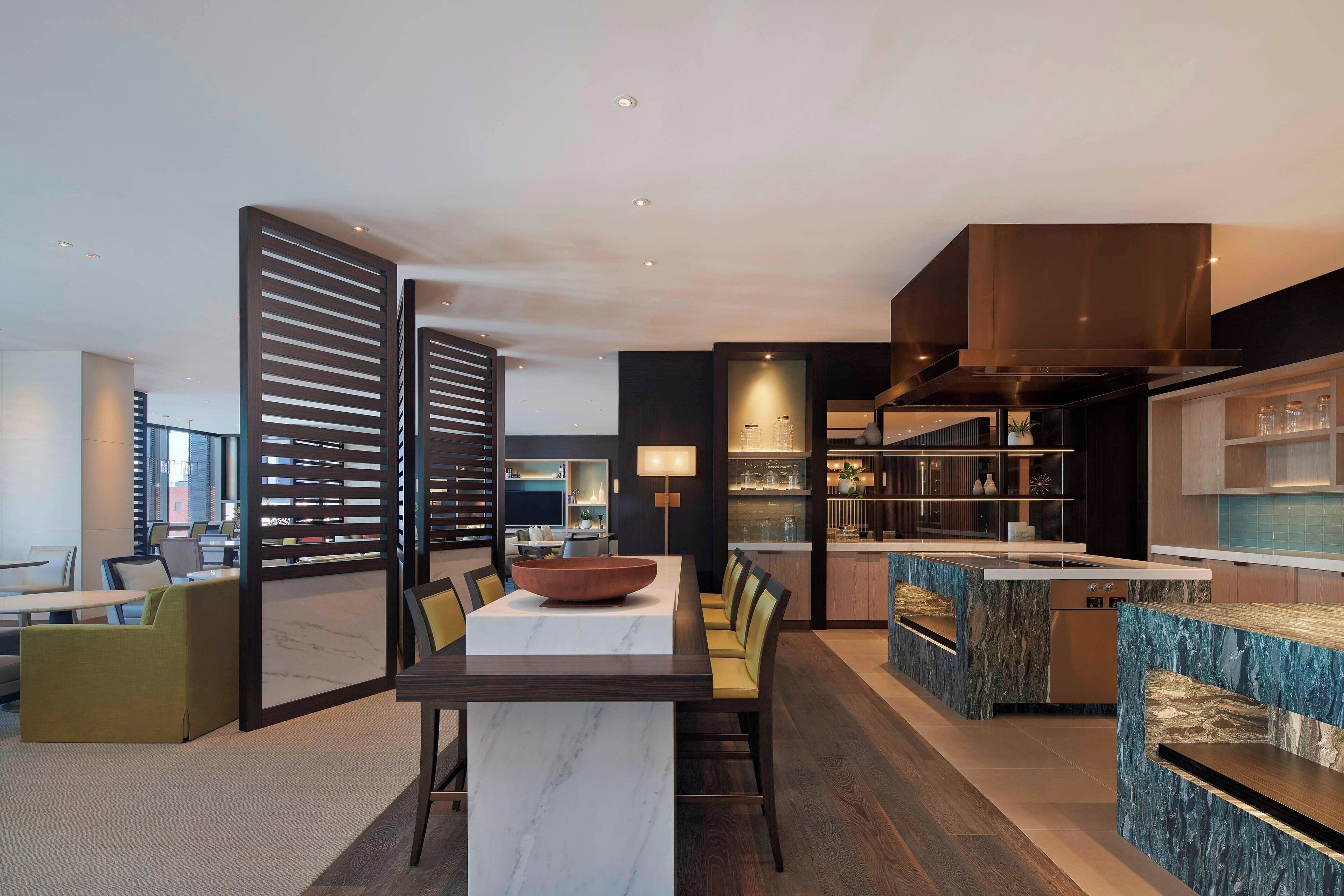 A modern kitchen with a marble island, built-in appliances, and a dining area with a large table and chairs.