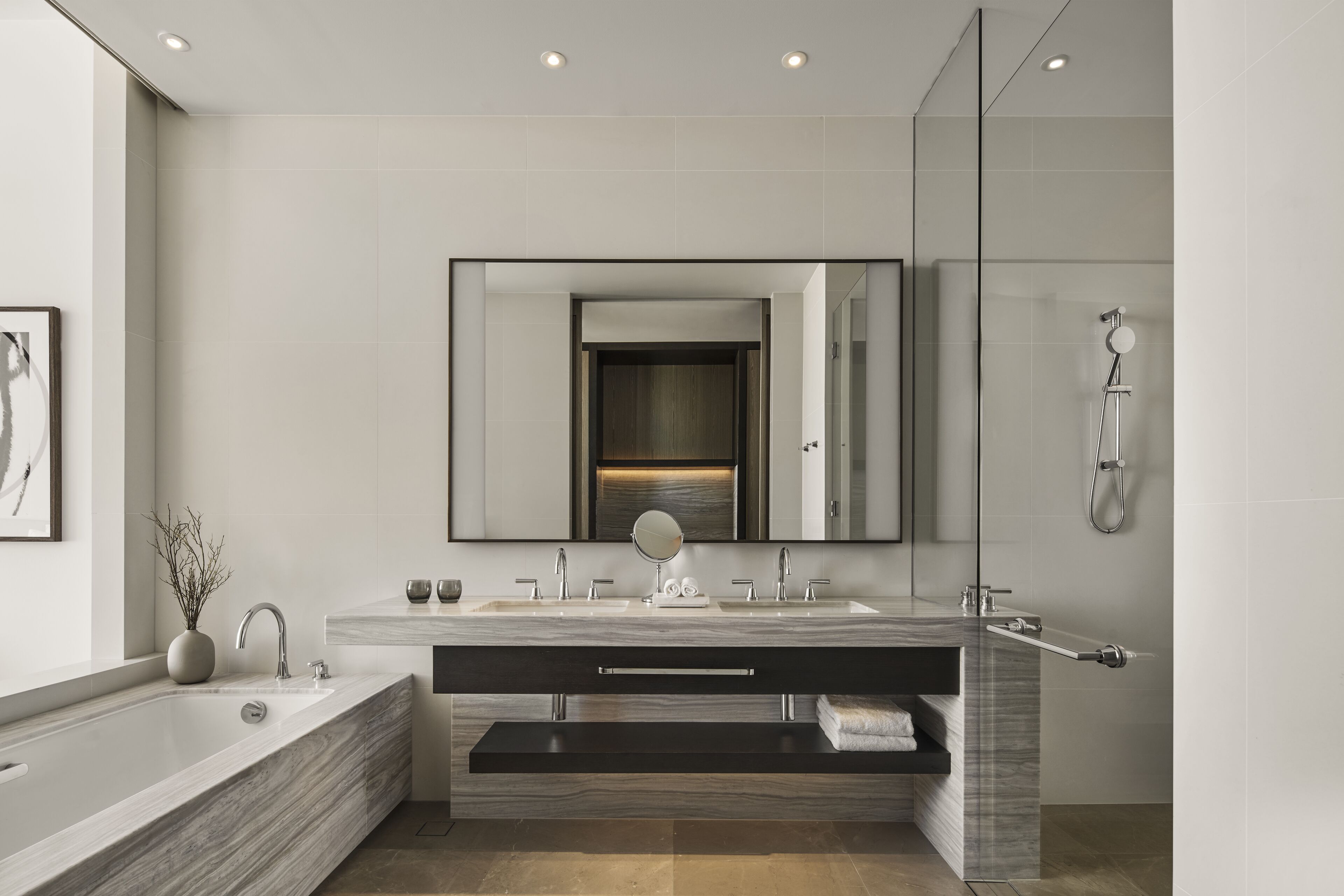 Un baño moderno con un espejo grande, lavamanos dobles, bañera y ducha.