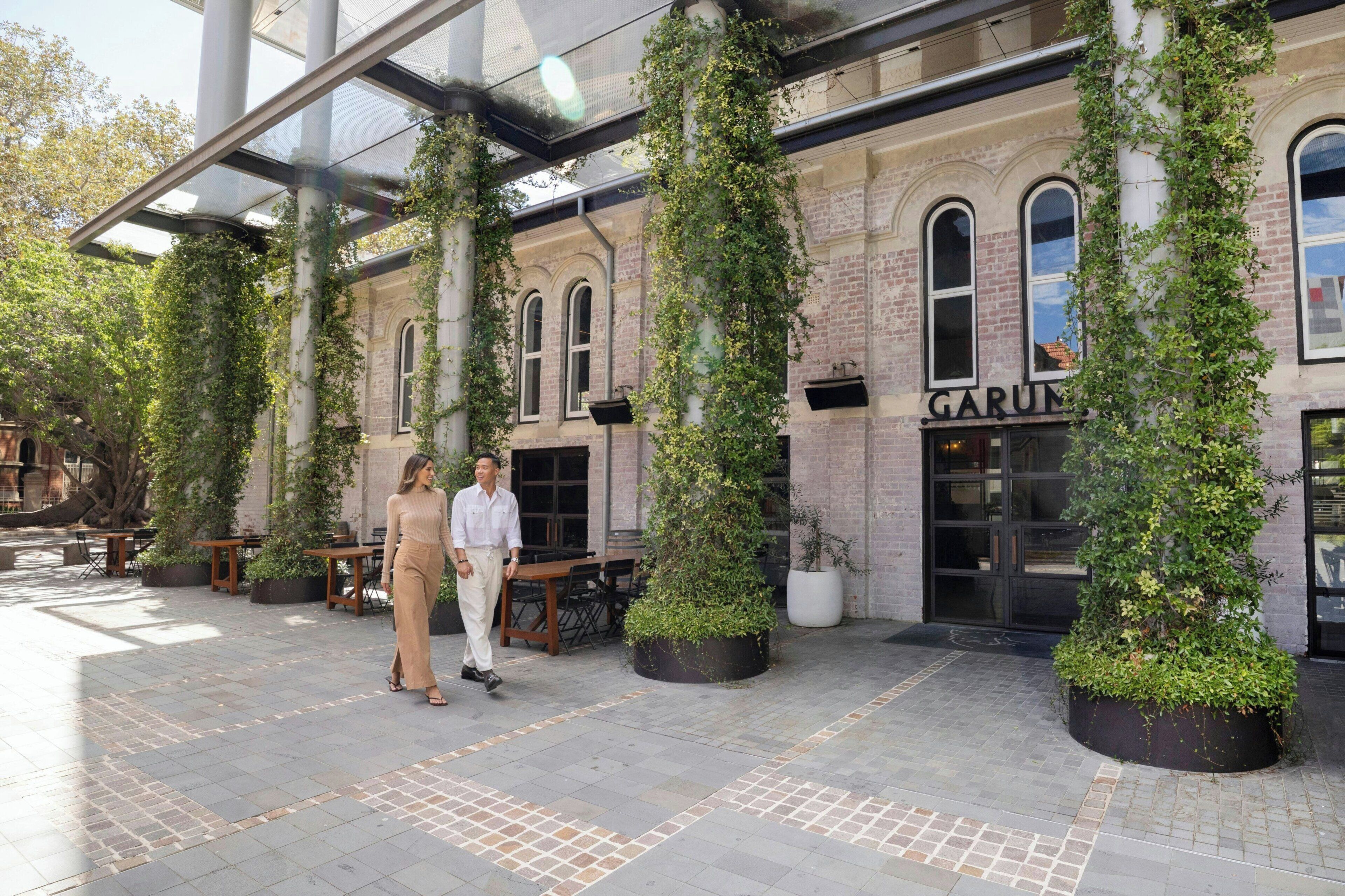 A covered outdoor area with a brick building, potted plants, and a sign that reads 'GARUM.'