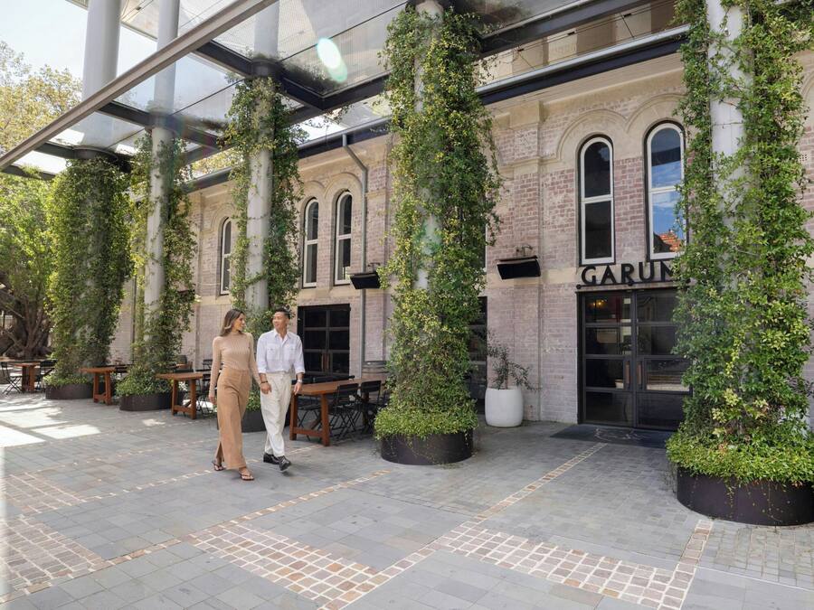 A covered outdoor area with a brick building, potted plants, and a sign that reads 'GARUM.'