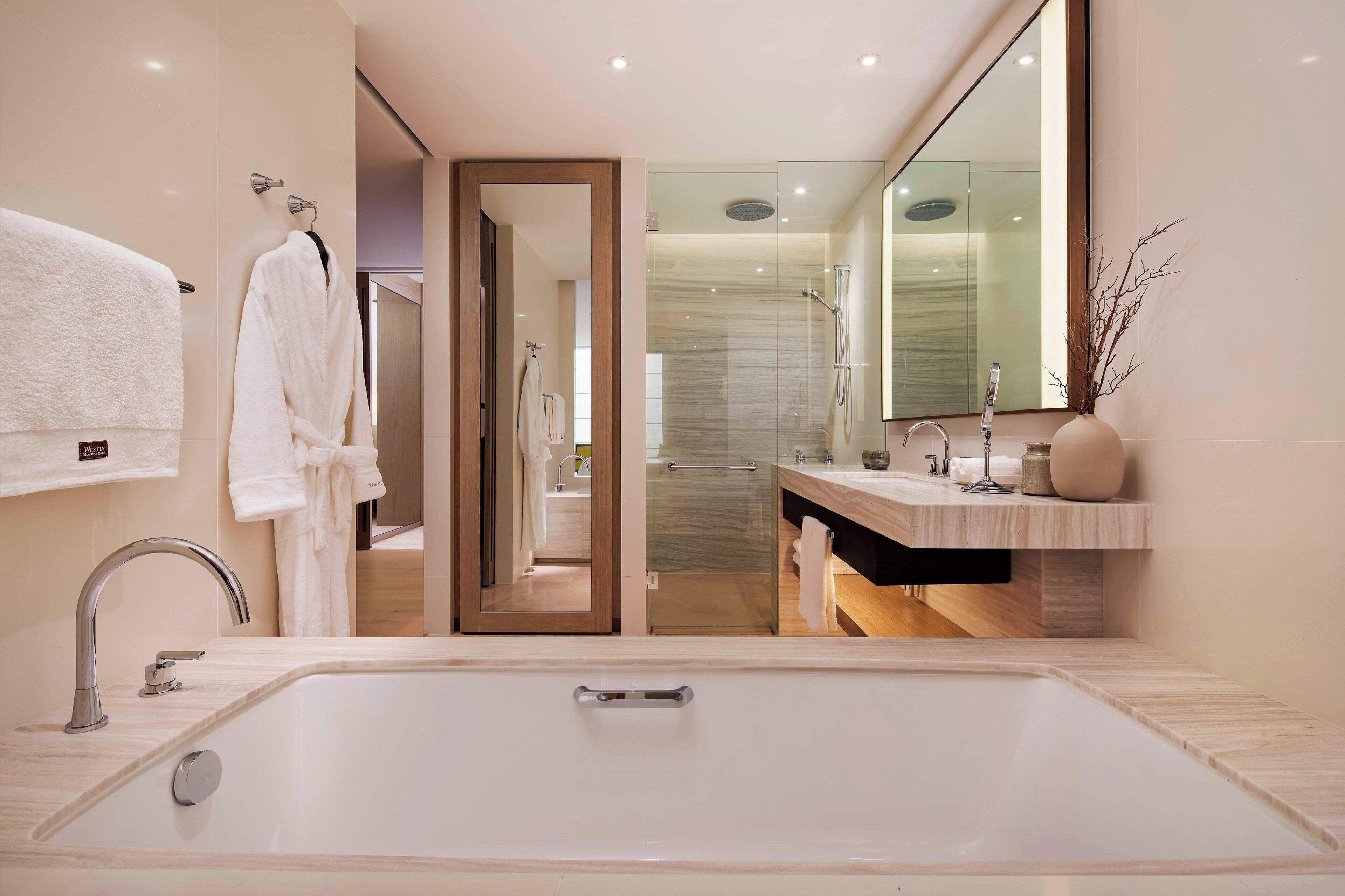 A modern bathroom with a large bathtub, a vanity with a mirror, and a shower area.