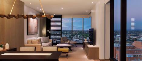 A modern living room with a dining area, large windows offering a city view, and a flat-screen TV on a wooden console.