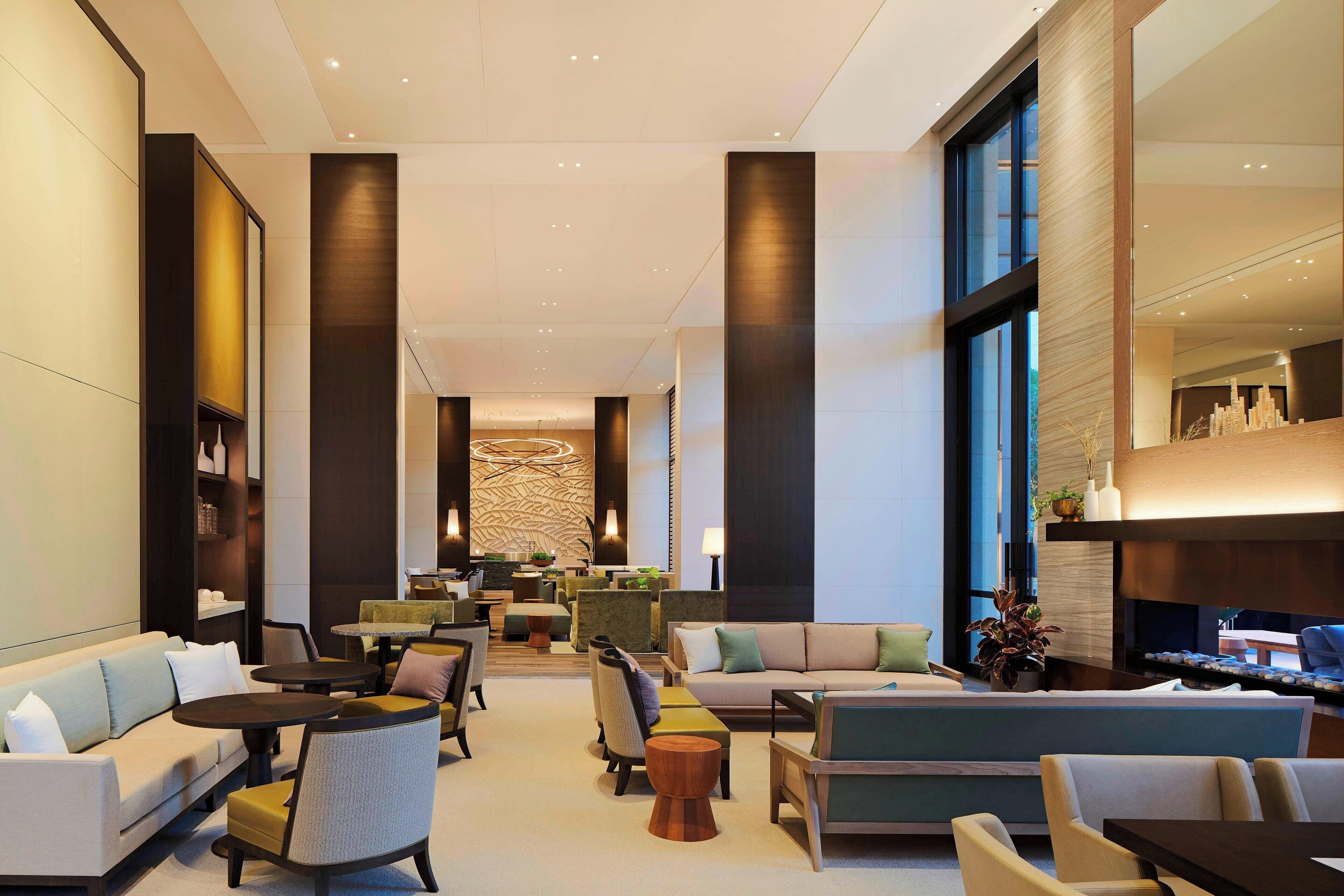 A spacious lobby with a sofa, chairs, tables, and a reception desk.