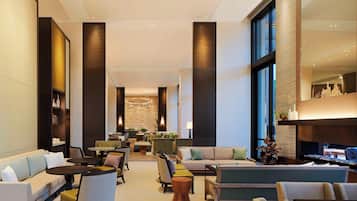 A spacious lobby with a sofa, chairs, tables, and a reception desk.