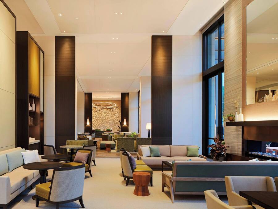 Een ruime lobby met een bank, stoelen, tafels en een receptiebalie.
