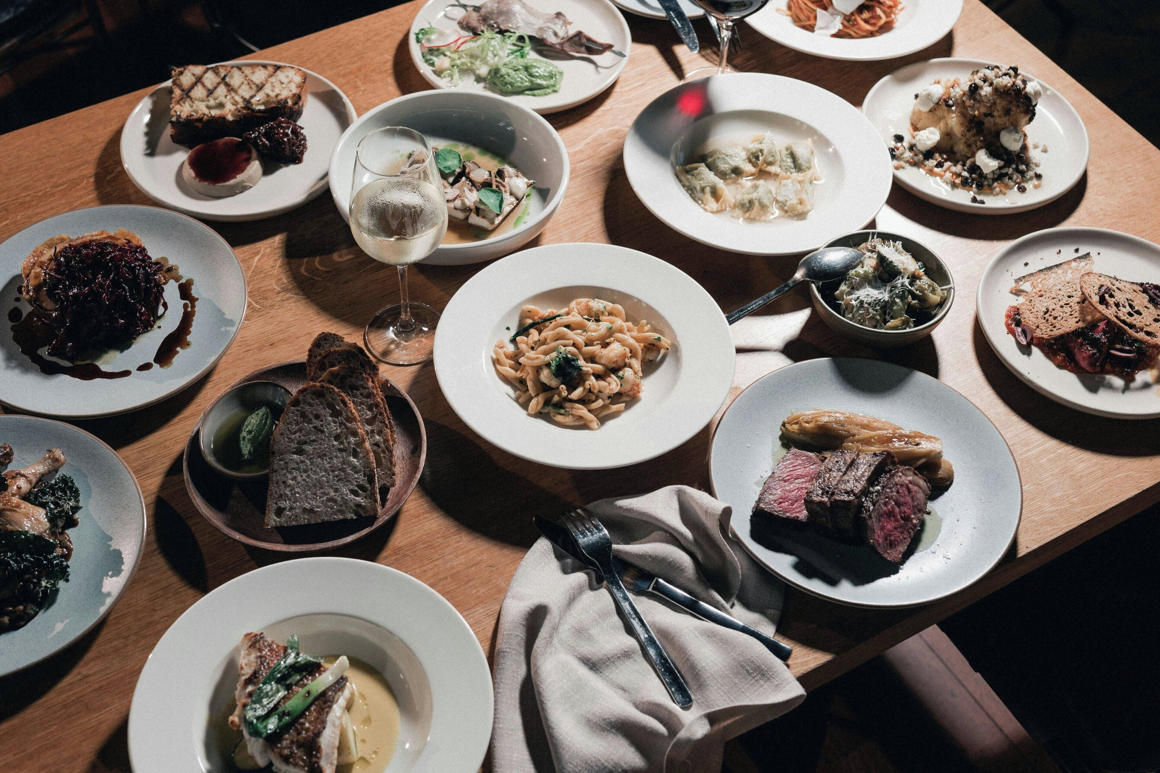 A dining table with various dishes, including pasta, meat, and desserts.