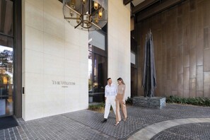 A building entrance with a sign reading 'The Westin Perth,' a modern architectural design, and a decorative metal sculpture.