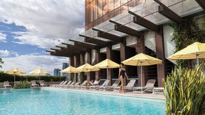 A swimming pool with sun umbrellas, lounge chairs, and a modern building with large windows. - The Westin Perth (Perth)