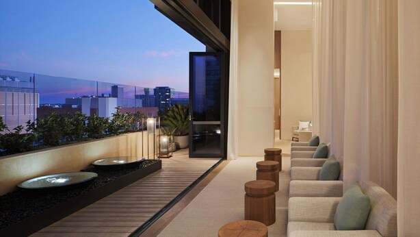 A modern interior with a seating area, a view of the cityscape, and a balcony with plants.