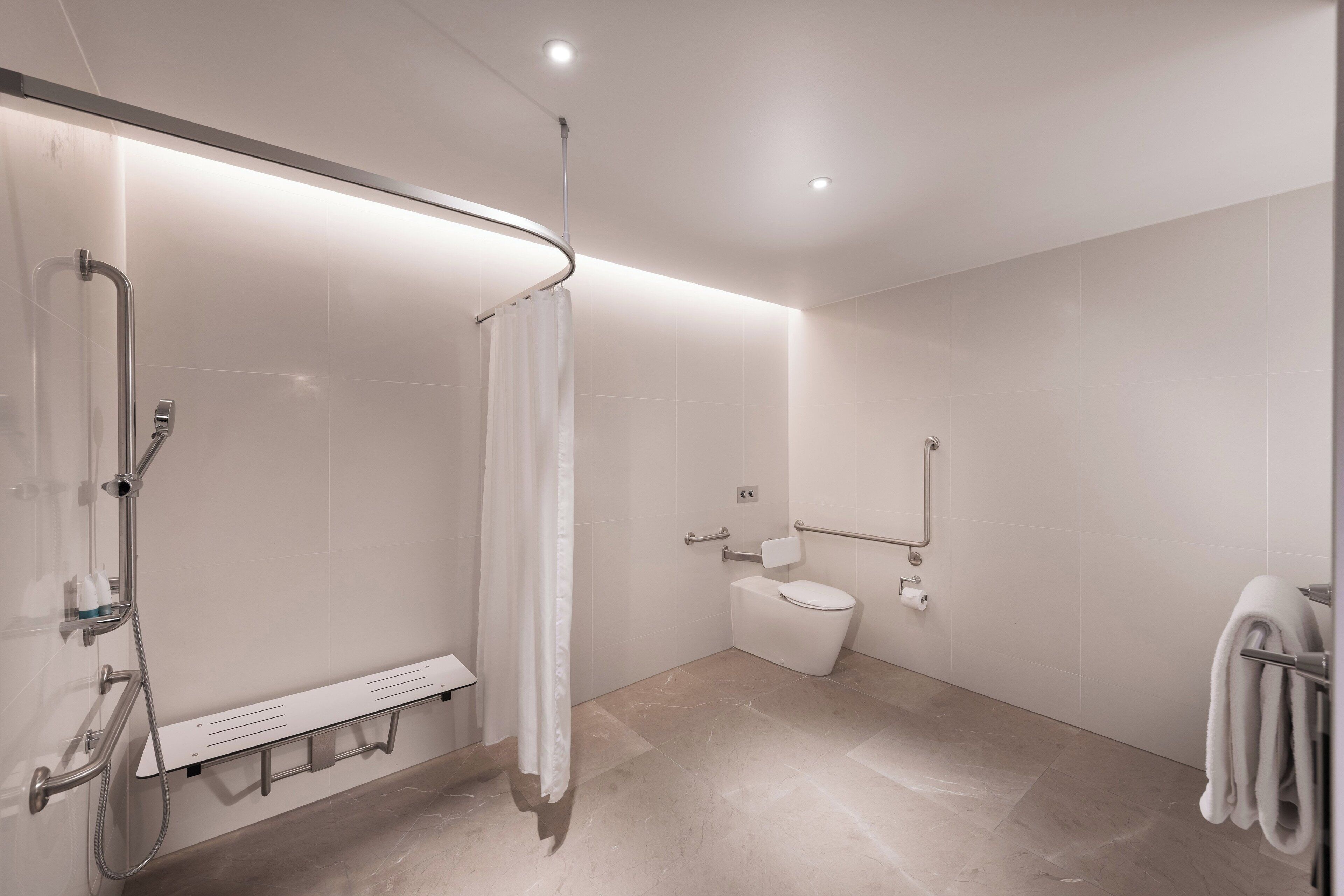 Uma casa de banho moderna com chuveiro, sanita e porta-toalhas.