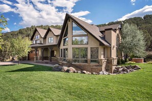 A two-story house with a large front porch, stone foundation, and a sloped roof. - Luxury MTN Home w/ Hot Tub, Views & Near Skiing! (Basalt)