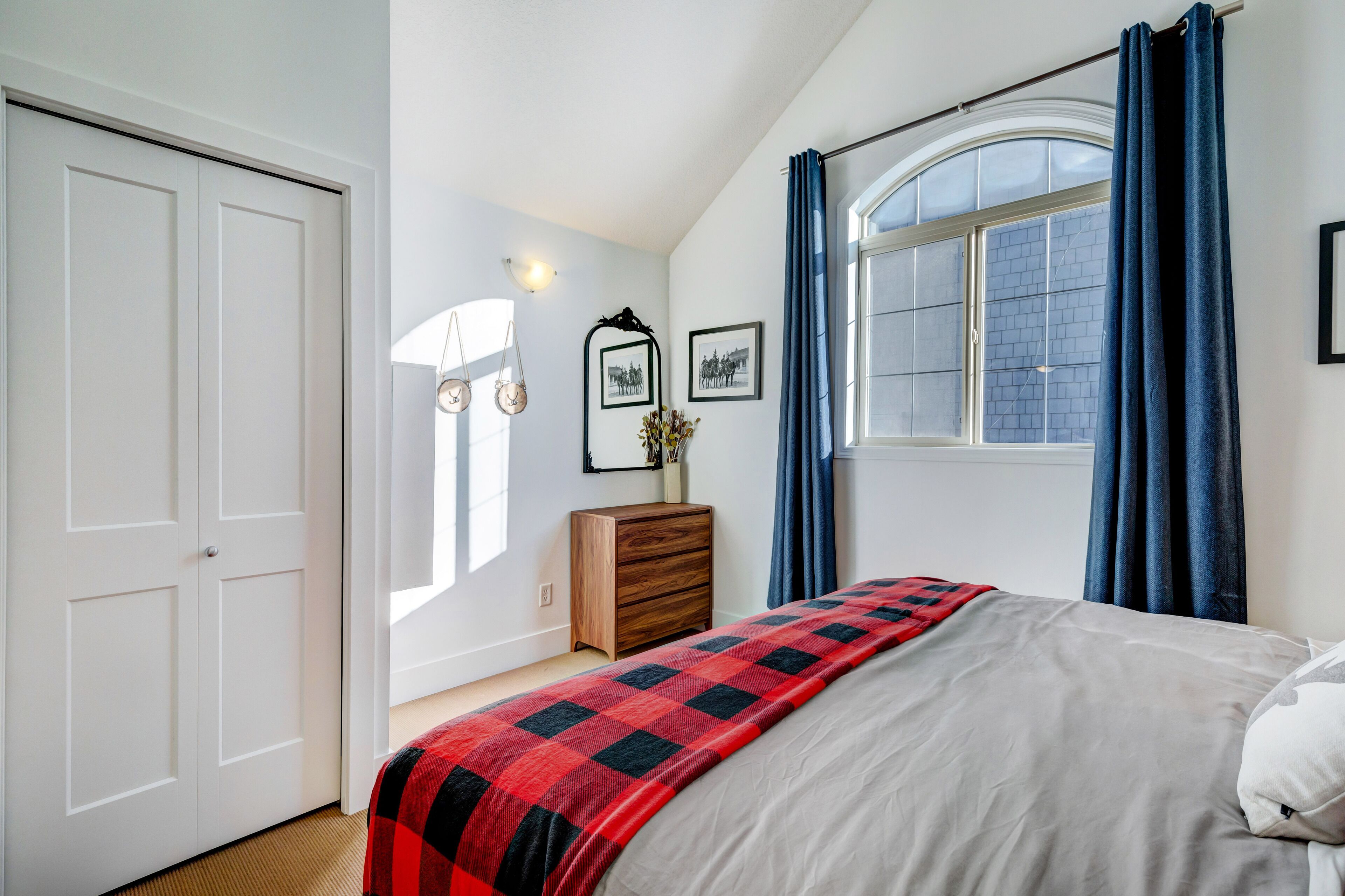 Un dormitorio con cama, cómoda, ventana con cortinas y puerta.