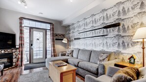 A cozy living room with a fireplace, a sofa, a coffee table, and a television.