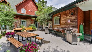A wooden cabin with a stone foundation, outdoor seating, and a barbecue grill.