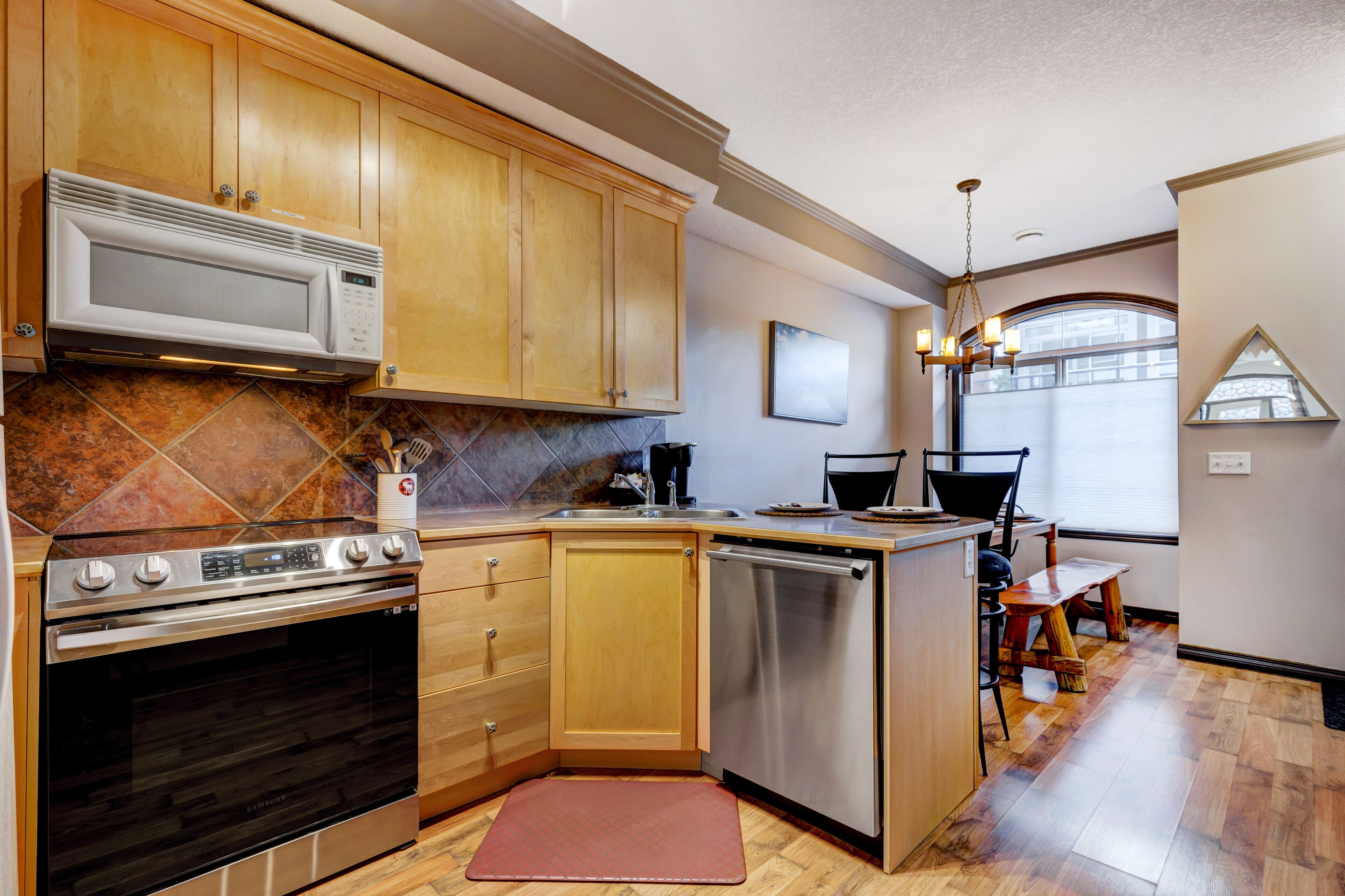 A kitchen with wooden cabinets, stainless steel appliances, and a dining area with a table and chairs.