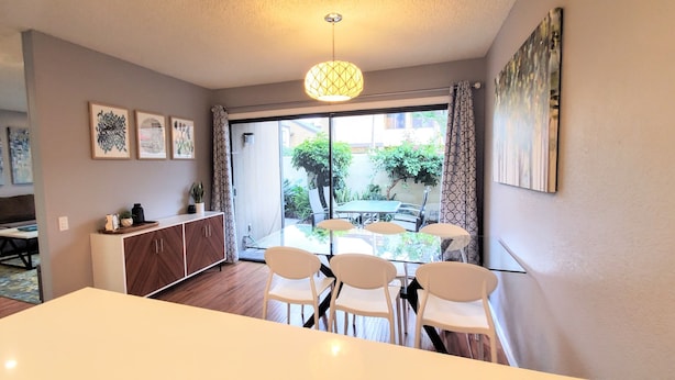 Una sala de estar moderna con comedor, un sofá, una vitrina y un ventanal con vistas al exterior.