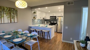 Una cocina moderna con gabinetes blancos, electrodomésticos de acero inoxidable y una isla central.