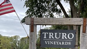 Skilt for Truro Vineyards med en cirkulær logo for South Hollow Distillery.
