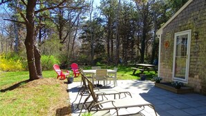 En terrasse med et bord, stole, et picnicbord og krukkeplanter.
