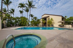 Una piscina con sillas de descanso y palmeras.