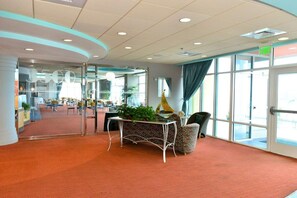 Un hall d’entrée spacieux doté d’un plafond incurvé, d’un comptoir de réception et d’une grande fenêtre offrant une vue sur l’extérieur.
