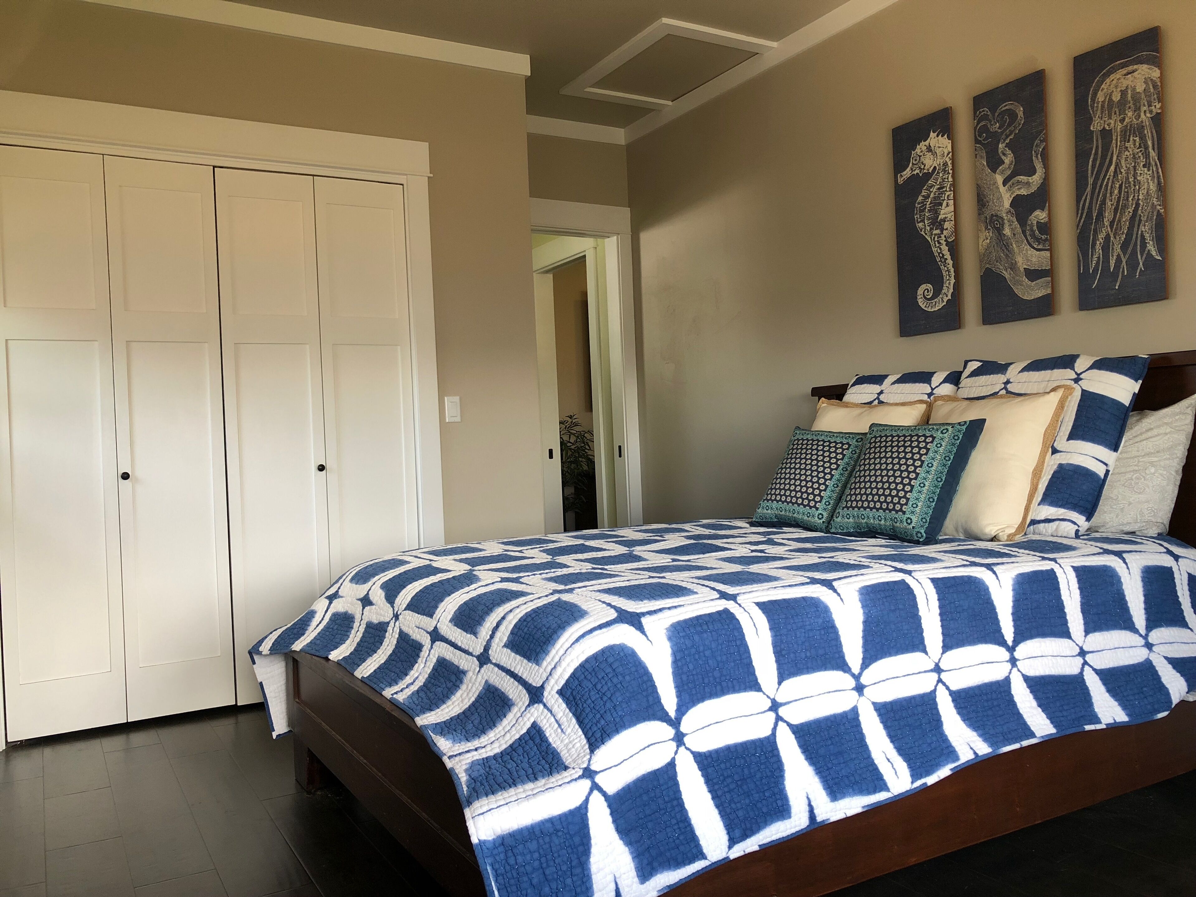 A bedroom with a large bed, a wardrobe, and three wall-mounted artworks.