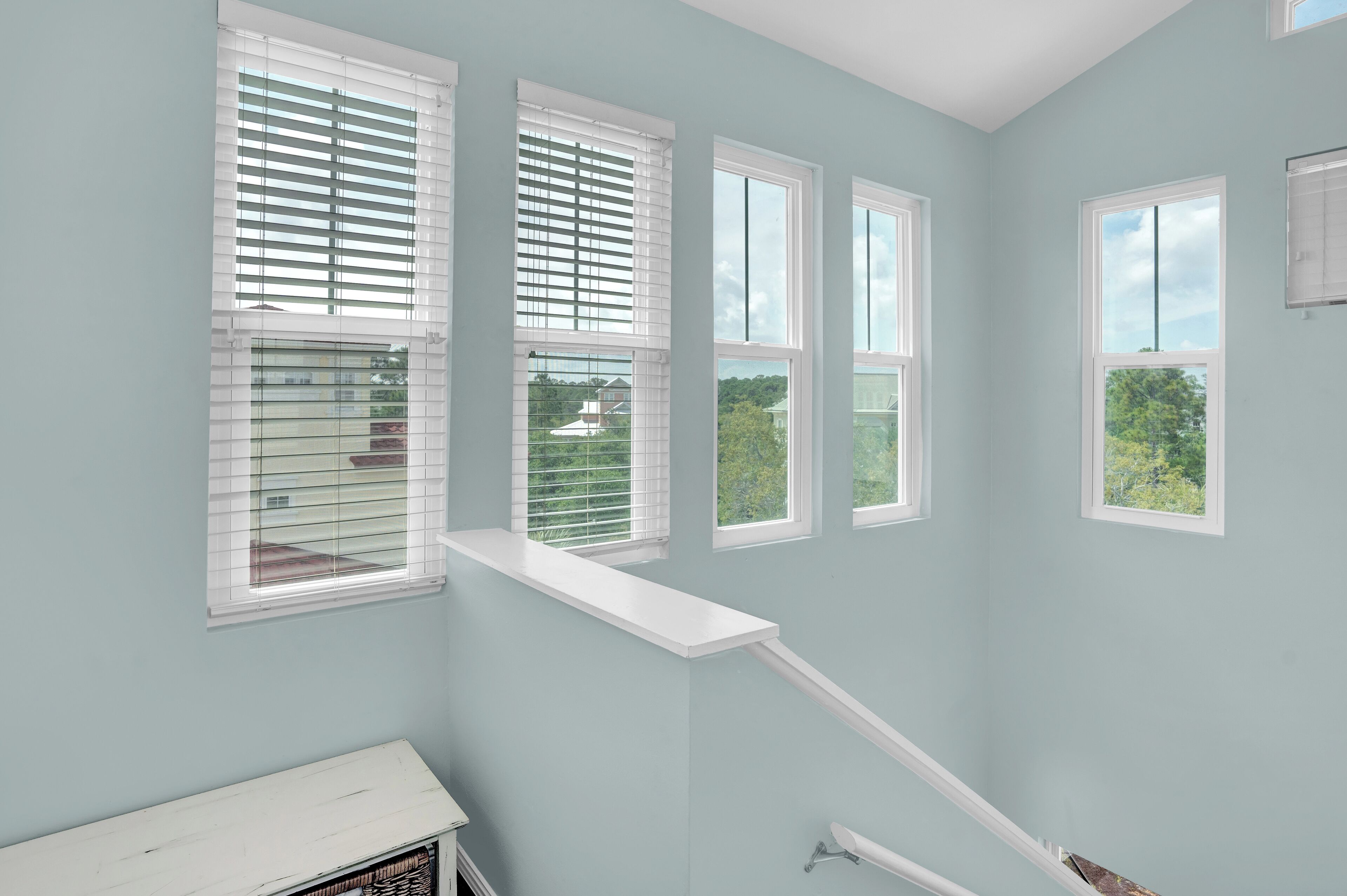 A room with large windows, a white bench, and a view of greenery outside.