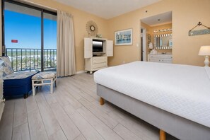 Une chambre d’hôtel avec un balcon, un lit, une télévision, une commode et une salle de bain.