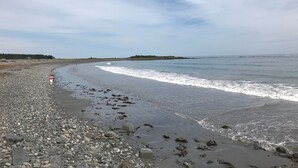 A pebbly beach with gentle waves, a distant shoreline, and a clear sky. - 600' of Waterfront Chauncey Creek House, fenced yard, office, walk to the beach (Kittery)