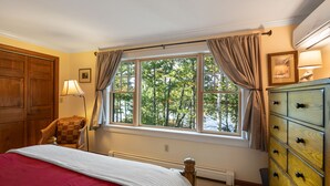 A bedroom with a large window, a wooden dresser, a chair, and a bed with a red blanket. - 600' of Waterfront Chauncey Creek House, fenced yard, office, walk to the beach (Kittery)