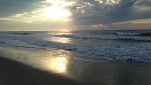 Una playa con olas y cielo nublado.