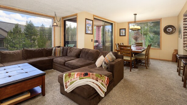 A living room with a sectional sofa, a coffee table, and a dining area with a table and chairs.
