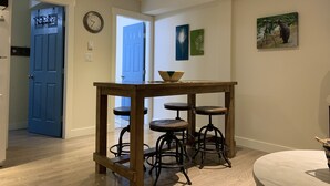 Un coin repas avec une table en bois et des tabourets de bar, une horloge au mur et des œuvres d’art.