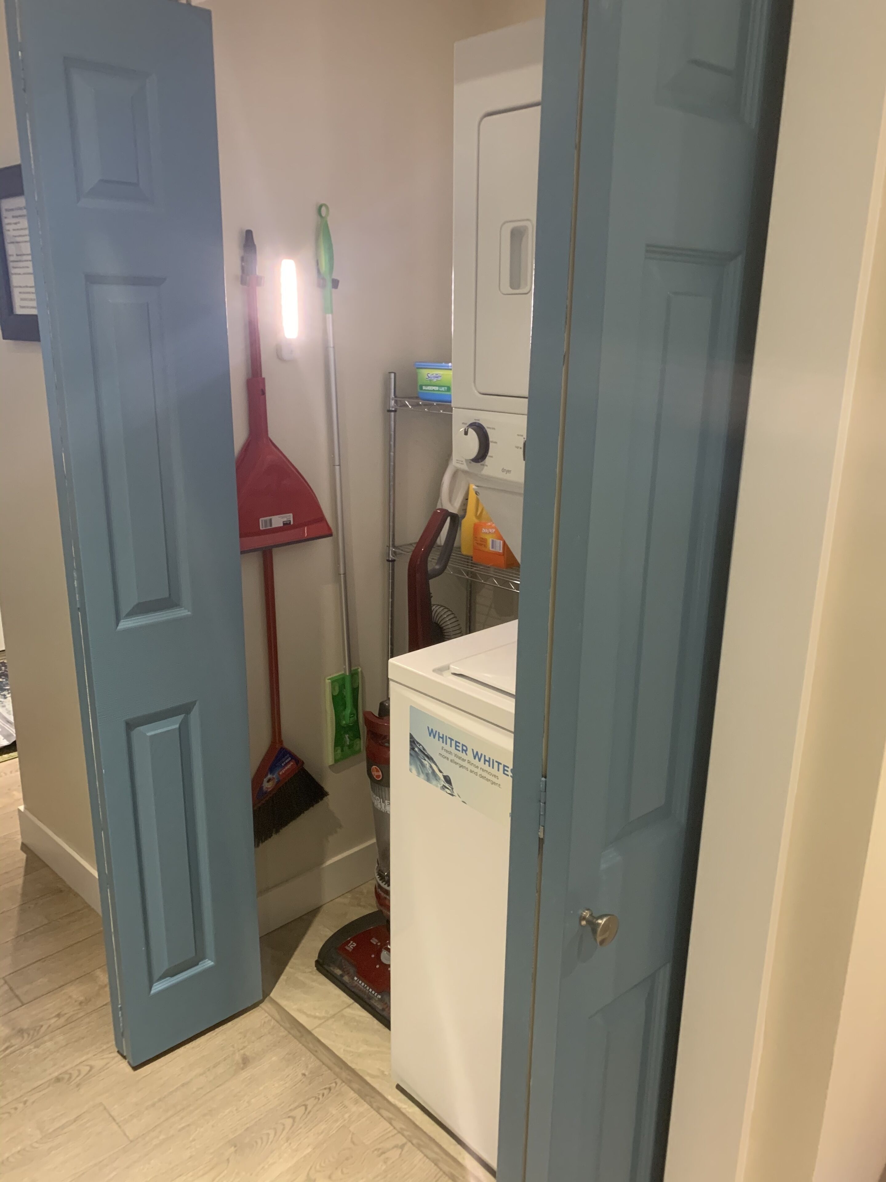 Un cuarto de lavandería con lavadora, un trapeador y productos de limpieza.