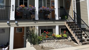 Un immeuble résidentiel de deux étages doté d’un porche à l’avant, d’un escalier et de jardinières.