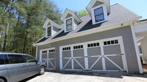 A two-story house with a garage and a car parked in front.