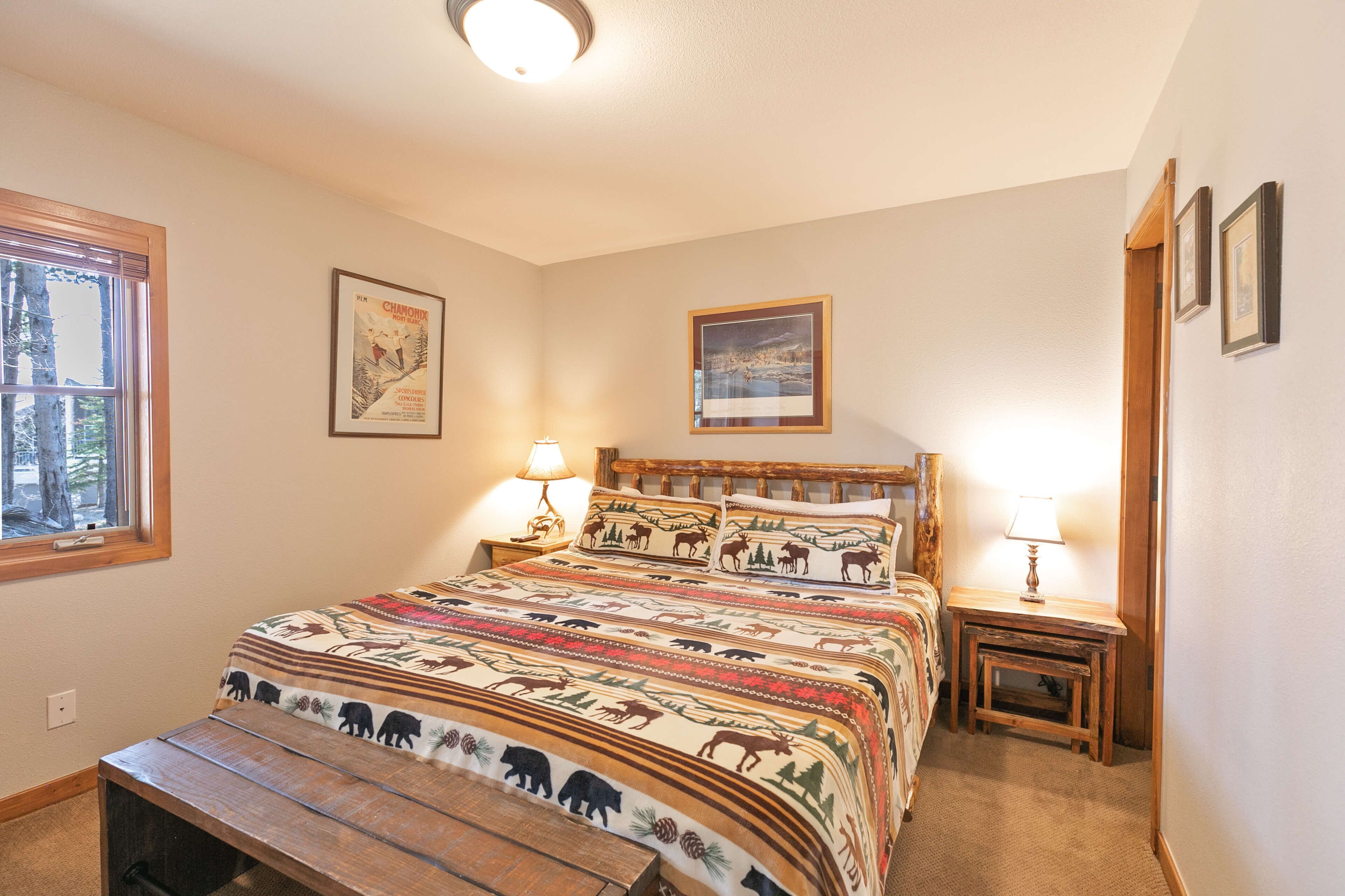 A bedroom with a large bed, two bedside tables, a bench, and two wall-mounted lamps.