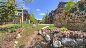 Una zona residencial con varias casas, un gran letrero de Los Piños Condominio y un jardín bien cuidado con rocas y arbustos.