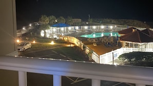 A nighttime view of a resort with a pool area, a fenced deck, and a parking lot. - Perfect condo for your getaway.  (N Topsail Beach)
