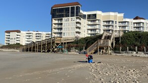 A beachfront hotel with multiple balconies, a wooden walkway, and a sandy beach. - Perfect condo for your getaway.  (N Topsail Beach)