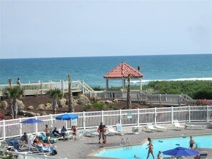A pool area with lounge chairs and umbrellas, a gazebo, and a view of the ocean. - Perfect condo for your getaway.  (N Topsail Beach)