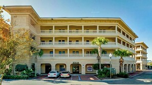 Experience the charm of this colonial-style hotel, featuring a symmetrical facade with balconies on each floor and a landscaped area with palm trees.