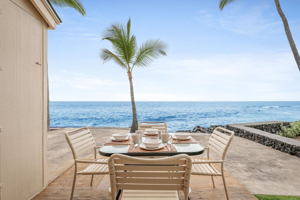 An outdoor dining area with a table set for four, overlooking the ocean.