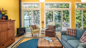 A cozy living room with a large window, a wooden cabinet, a sofa, and a coffee table. - Orcas Island, Casa Verde #269 (Eastsound)