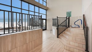 A staircase with a view of the beach, a sign indicating hot tub rules, and a blue hose on the right.
