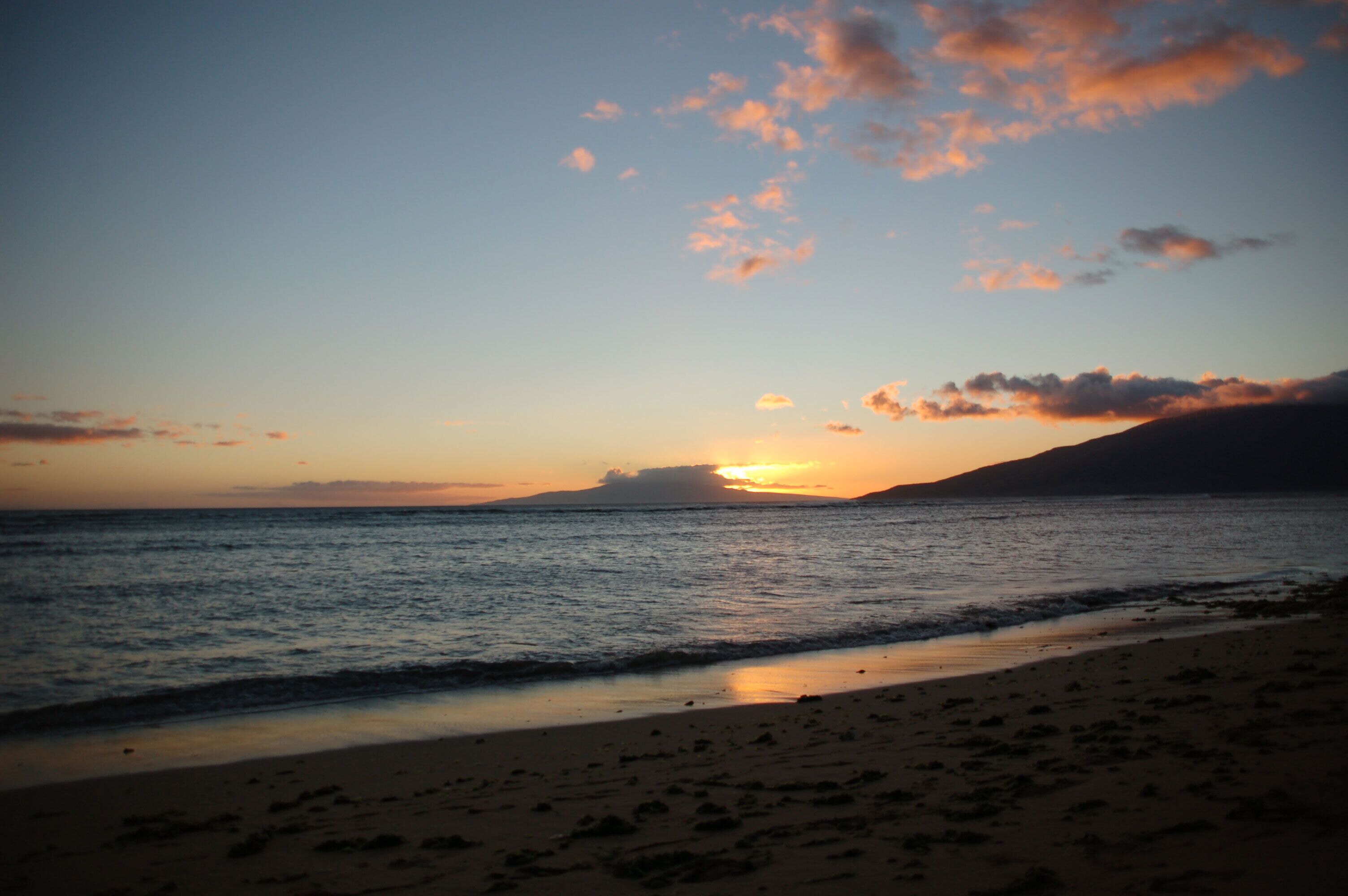 A beach with a sunset over the ocean.