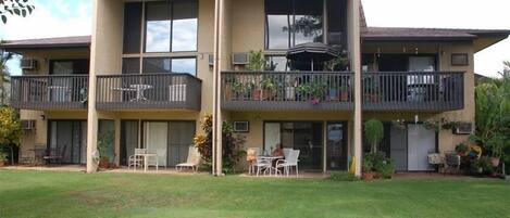 A two-story building with balconies, outdoor seating, and potted plants.
